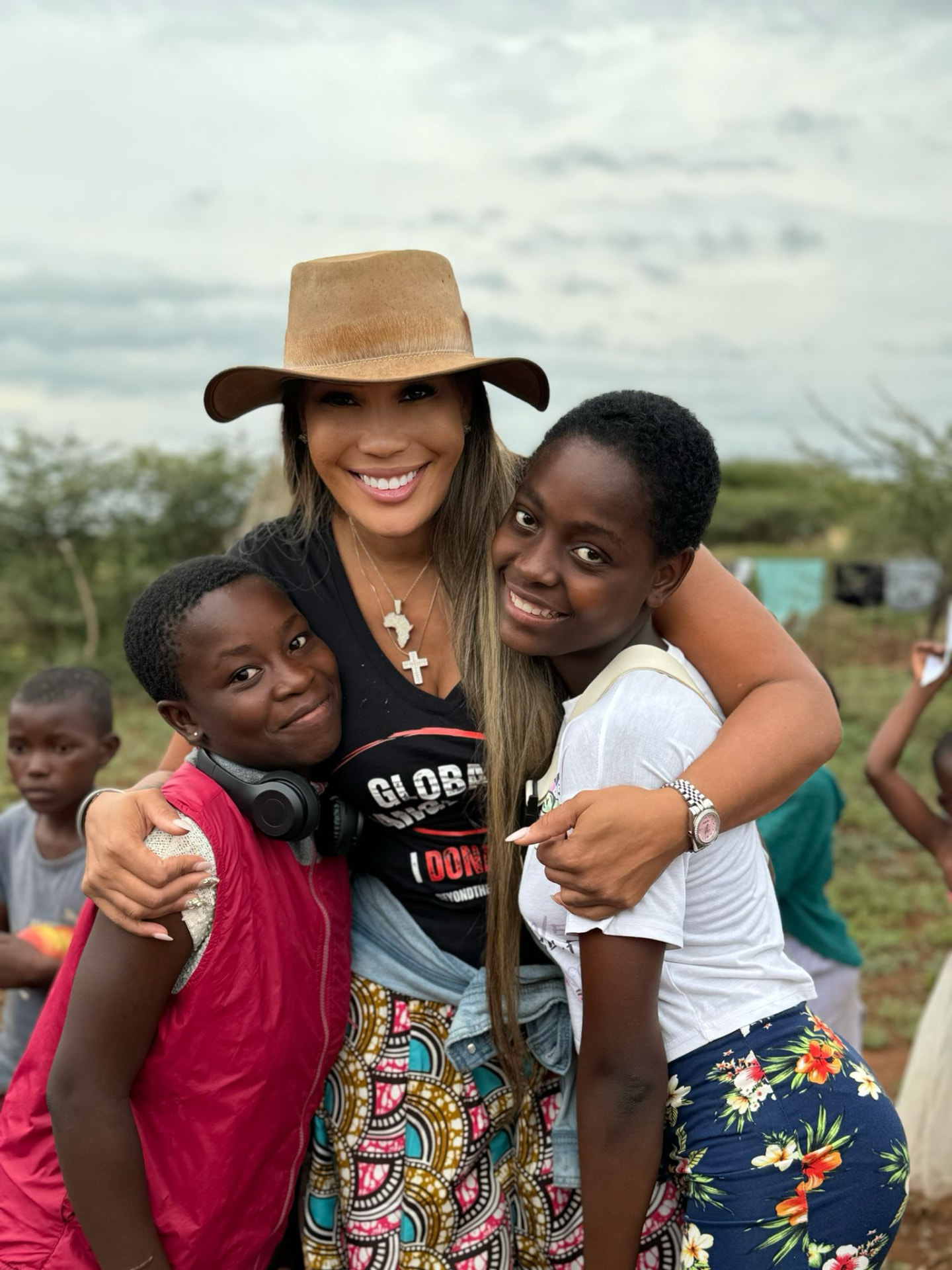 Dr Chanita Foster embracing two girls during a Beyond The Game purpose trip