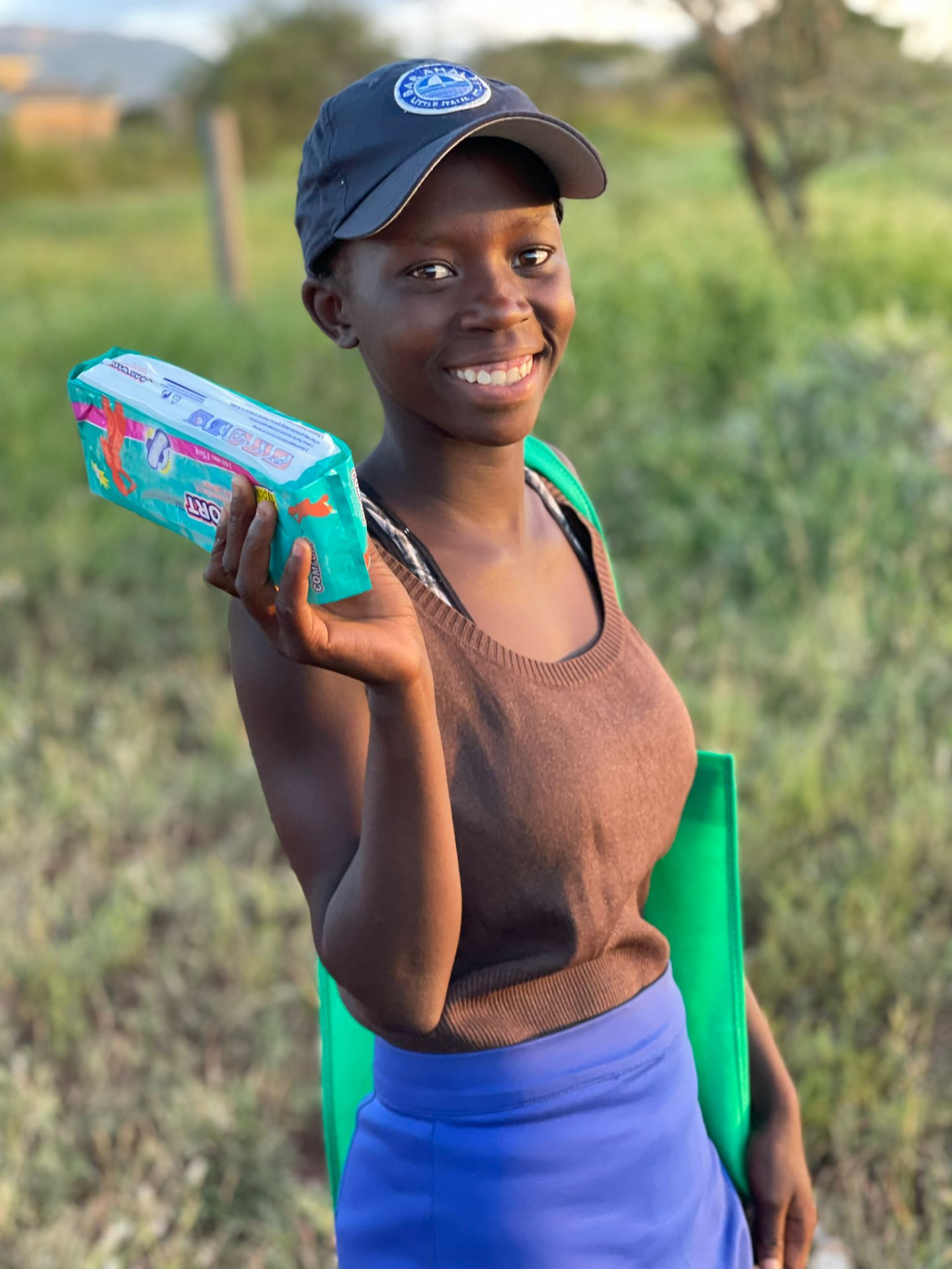 A smiling schoolgirl holding a pack of sanitary napkins