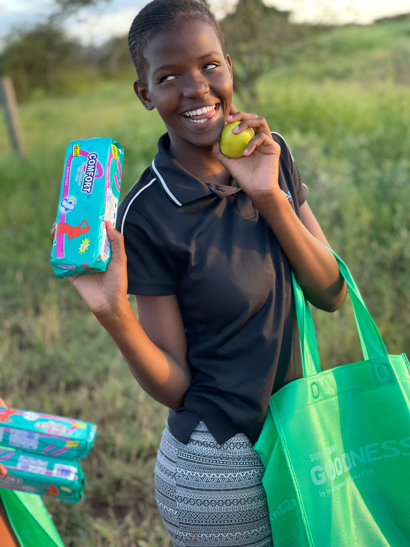 A young woman with a pack of sanitary napkins and fresh fruit in a Beyond The Game tote bag